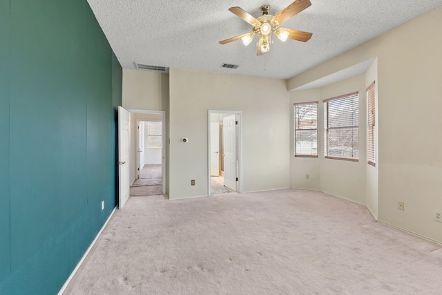 unfurnished bedroom with ceiling fan, light colored carpet, and a textured ceiling