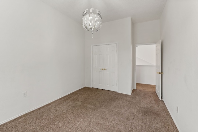 carpeted empty room featuring a notable chandelier