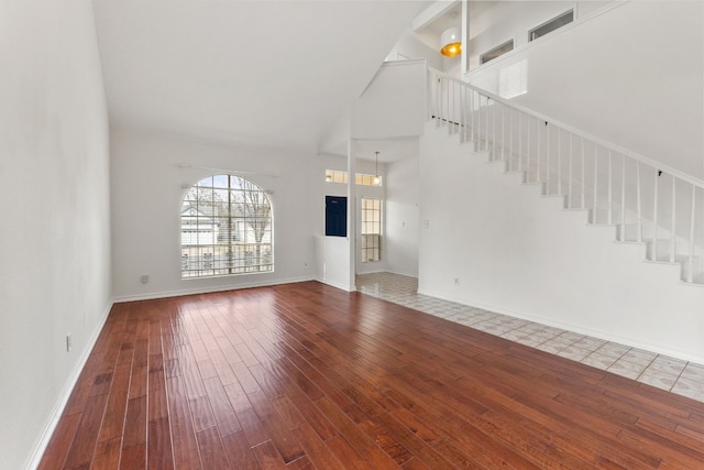 unfurnished living room featuring wood-type flooring and a high ceiling