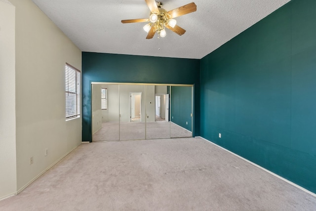 unfurnished bedroom with ceiling fan, light colored carpet, a closet, and a textured ceiling