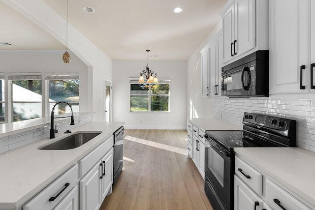 kitchen with sink, white cabinetry, decorative light fixtures, black appliances, and backsplash