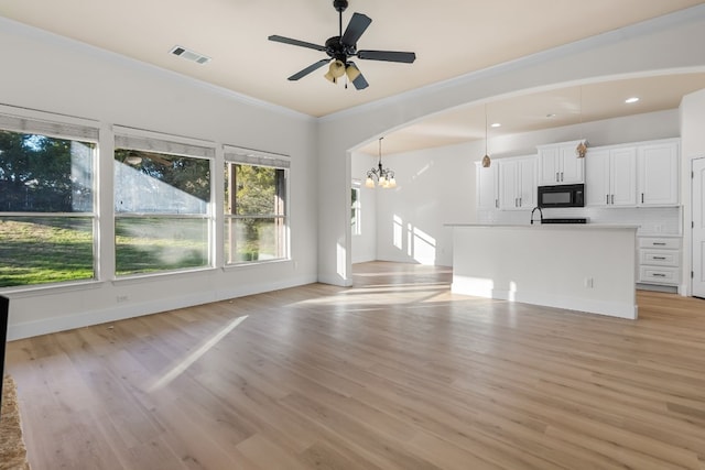 unfurnished living room featuring ceiling fan with notable chandelier, ornamental molding, and light hardwood / wood-style floors