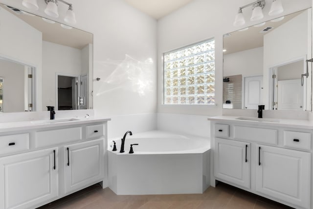 bathroom with tile patterned flooring, vanity, and a bath