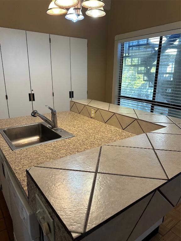 kitchen featuring a notable chandelier, dishwasher, sink, and white cabinets