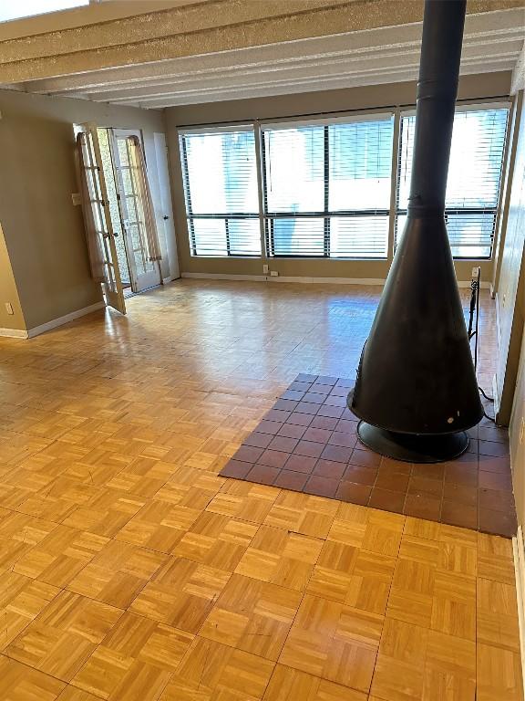 empty room featuring light parquet floors, plenty of natural light, and a wood stove