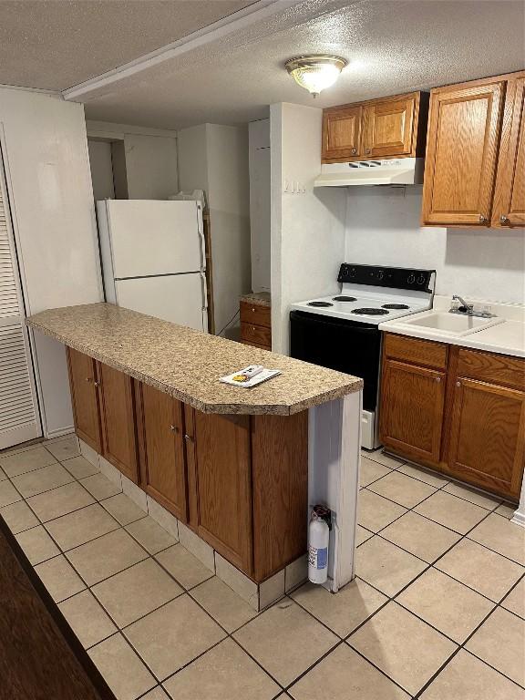 kitchen featuring sink, range with electric cooktop, a textured ceiling, light tile patterned flooring, and white fridge