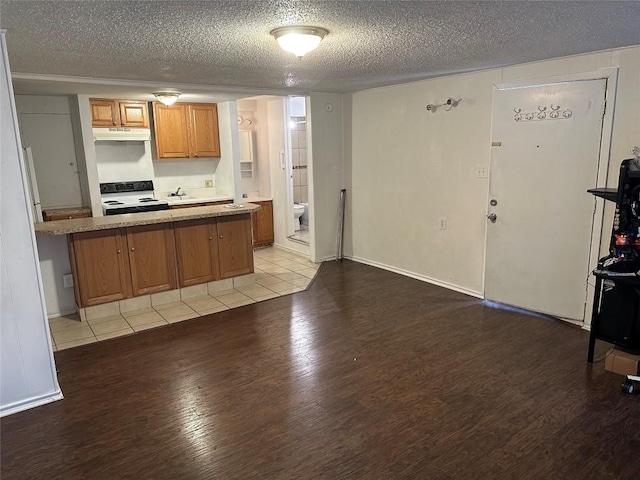 kitchen featuring kitchen peninsula, a textured ceiling, light hardwood / wood-style flooring, and range with electric stovetop