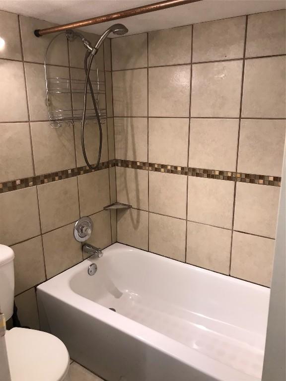 bathroom with tiled shower / bath combo, tile walls, and toilet