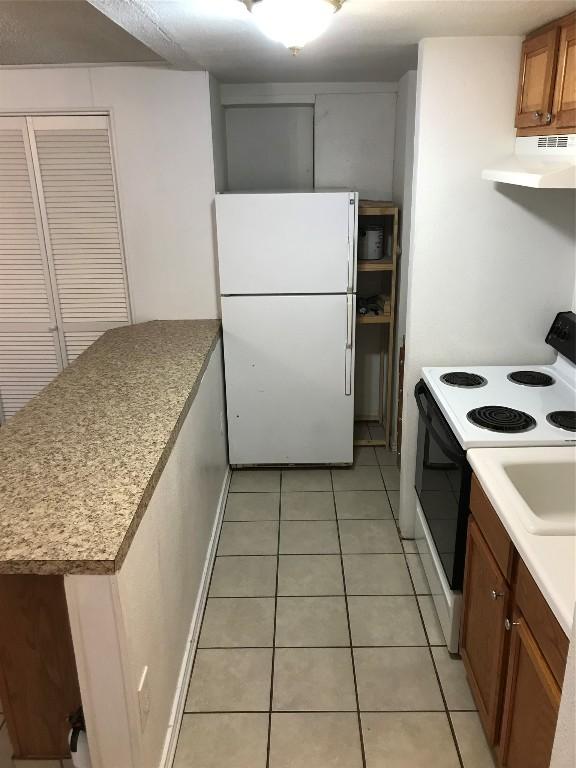 kitchen featuring light tile patterned flooring, white fridge, and electric stove