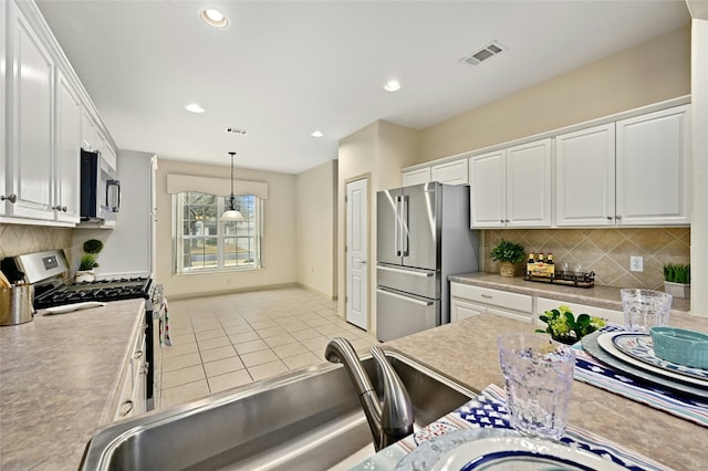 kitchen with tasteful backsplash, white cabinetry, appliances with stainless steel finishes, and decorative light fixtures