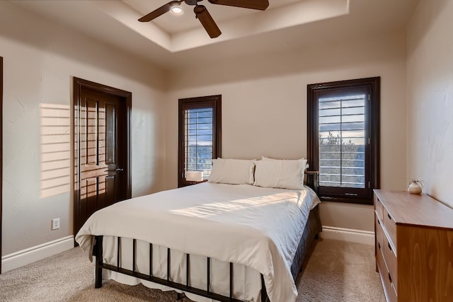 bedroom featuring a raised ceiling, ceiling fan, and carpet flooring