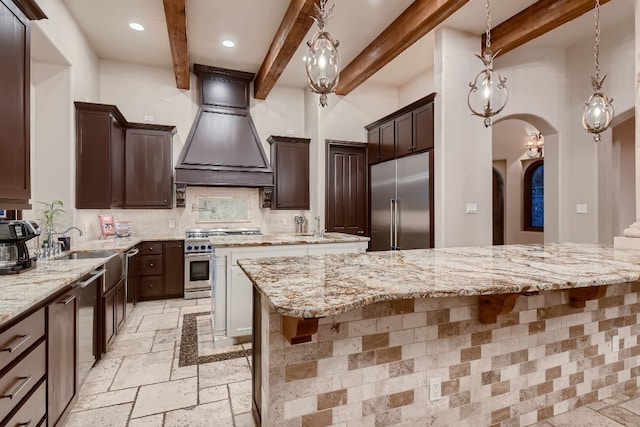 kitchen featuring high end appliances, a center island, light stone counters, and custom range hood