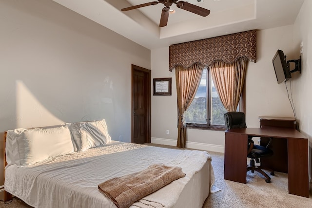 carpeted bedroom featuring a tray ceiling and ceiling fan