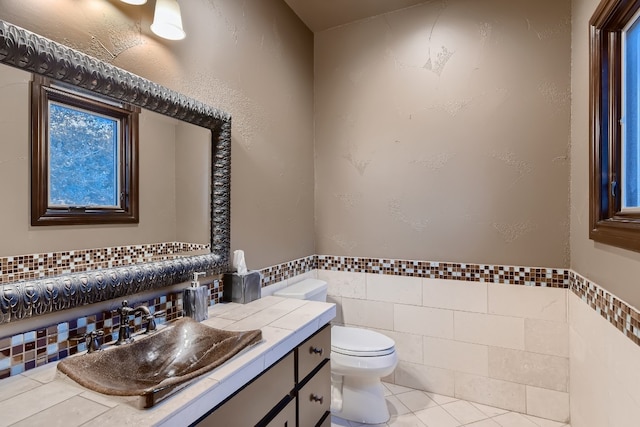 bathroom with tile patterned flooring, vanity, tile walls, and toilet