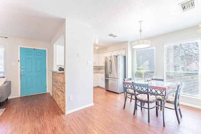 dining room with a healthy amount of sunlight, a textured ceiling, and light hardwood / wood-style flooring