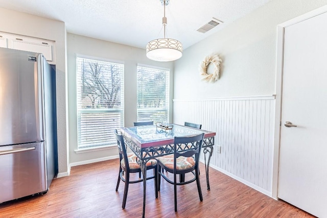 dining area featuring a textured ceiling and light wood-type flooring