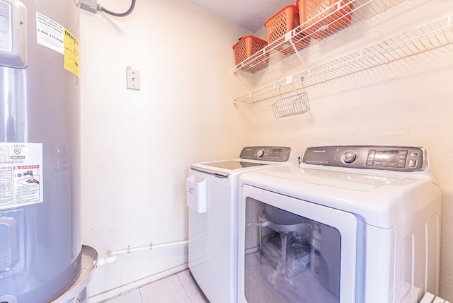 laundry area with light tile patterned flooring, washing machine and clothes dryer, and electric water heater