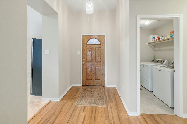 foyer entrance featuring separate washer and dryer and light hardwood / wood-style flooring