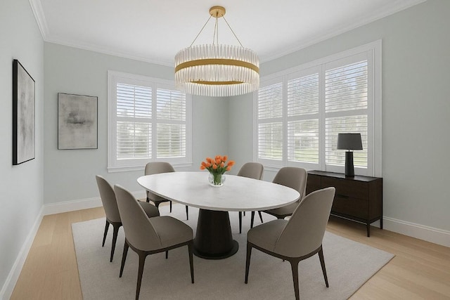 dining area featuring crown molding, light wood-style flooring, baseboards, and a chandelier