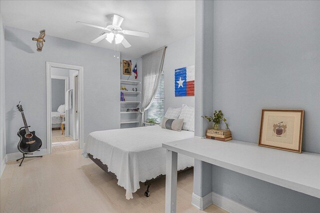 bedroom featuring light wood-type flooring, a ceiling fan, baseboards, and ensuite bath