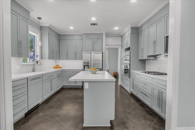 kitchen featuring crown molding, appliances with stainless steel finishes, a kitchen island, and tasteful backsplash