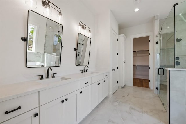 full bathroom featuring marble finish floor, a sink, a spacious closet, and a shower stall