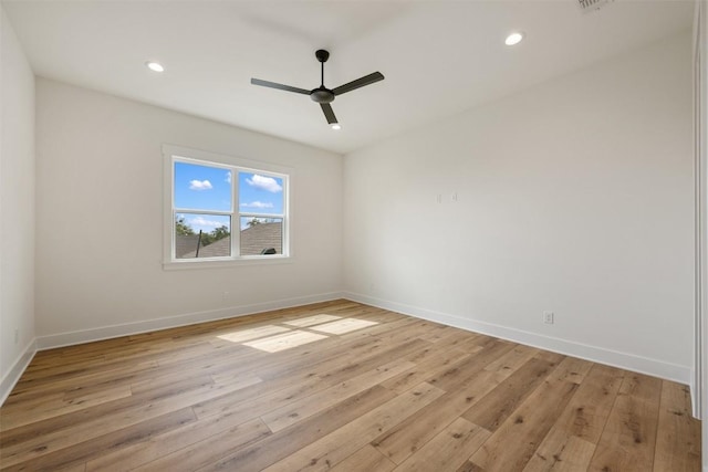 spare room featuring light wood finished floors, a ceiling fan, and baseboards