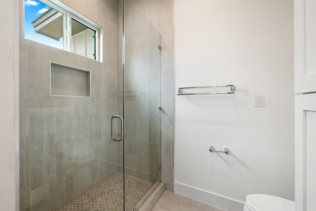 bathroom featuring tile patterned flooring, a shower stall, toilet, and baseboards