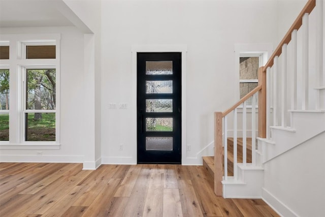 entrance foyer featuring stairway, light wood-style flooring, and baseboards