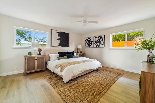 bedroom with ceiling fan, light hardwood / wood-style floors, and multiple windows