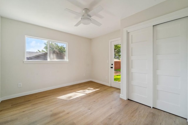 unfurnished bedroom with ceiling fan, multiple windows, and light wood-type flooring