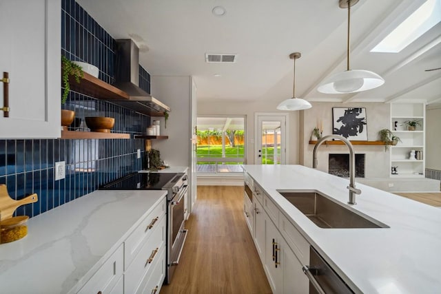 kitchen with pendant lighting, white cabinetry, high end stainless steel range, and sink