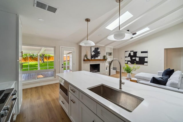 kitchen with pendant lighting, sink, stainless steel stove, and light stone countertops