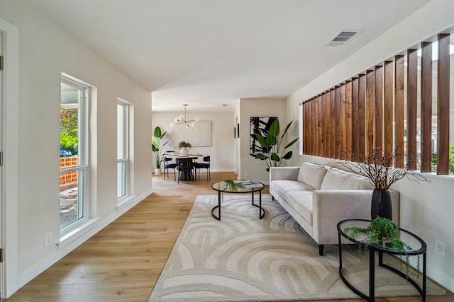 living room with an inviting chandelier, plenty of natural light, and light hardwood / wood-style floors