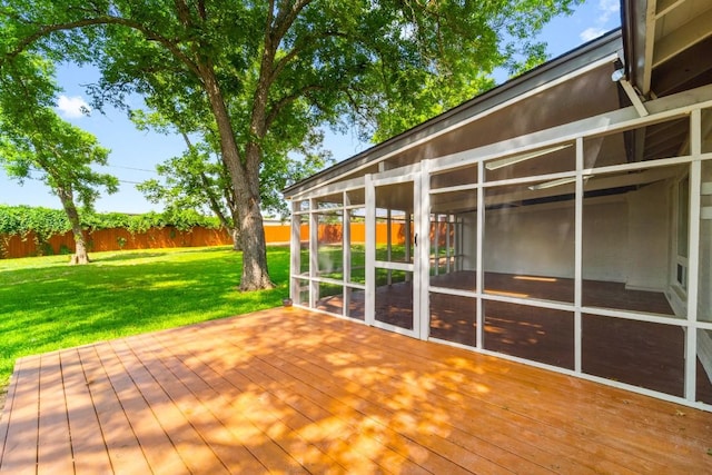 wooden terrace featuring a sunroom and a lawn