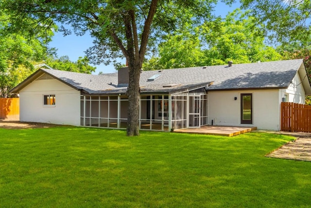 rear view of property featuring a sunroom, a patio area, and a lawn