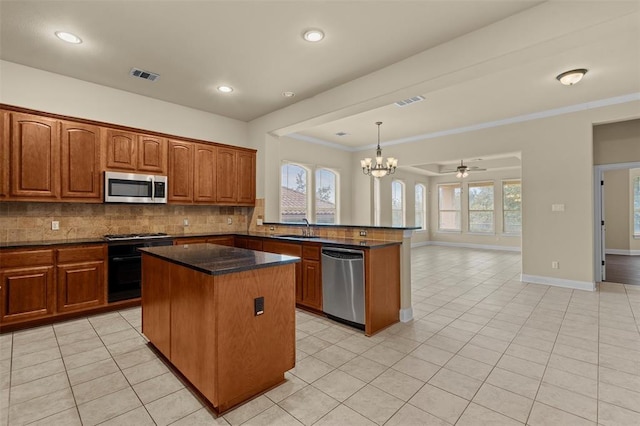 kitchen with pendant lighting, sink, stainless steel appliances, a center island, and tasteful backsplash