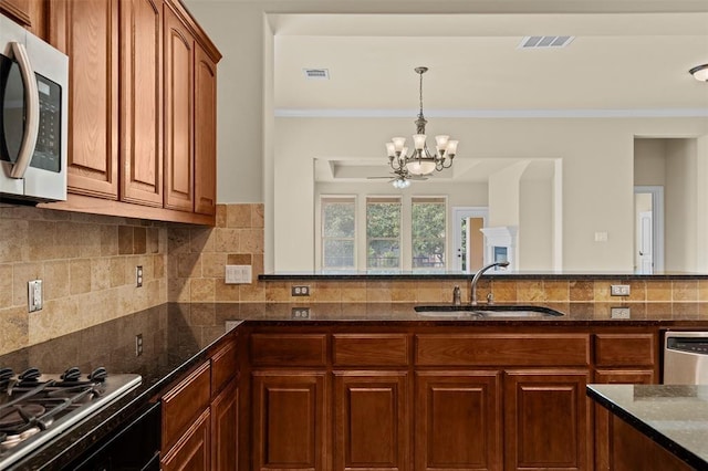 kitchen featuring sink, crown molding, dark stone countertops, stainless steel appliances, and decorative backsplash