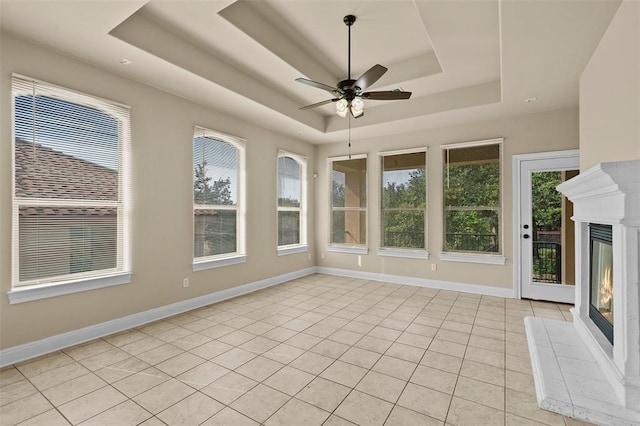 unfurnished sunroom featuring ceiling fan and a tray ceiling