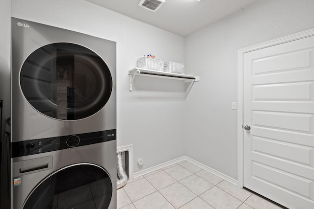 laundry room featuring stacked washing maching and dryer and light tile patterned flooring