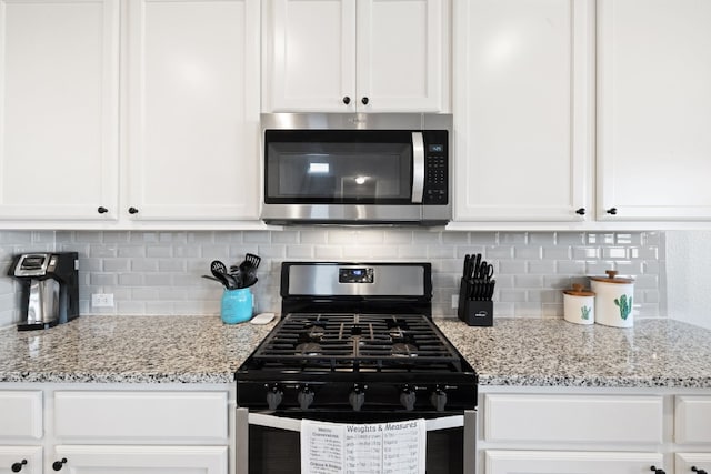 kitchen with white cabinetry, appliances with stainless steel finishes, light stone countertops, and backsplash