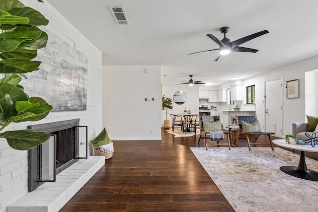 living room featuring ceiling fan, a fireplace, and hardwood / wood-style floors