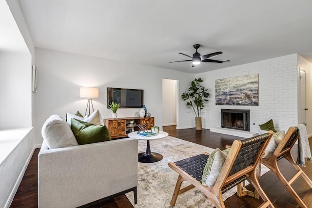 living room featuring ceiling fan, a brick fireplace, and dark hardwood / wood-style flooring