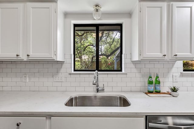 kitchen with dishwasher, sink, light stone countertops, and white cabinets