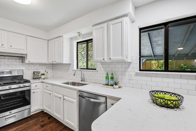 kitchen with sink, white cabinetry, dark hardwood / wood-style flooring, stainless steel appliances, and backsplash