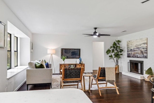 living room featuring ceiling fan, dark wood-type flooring, and a fireplace