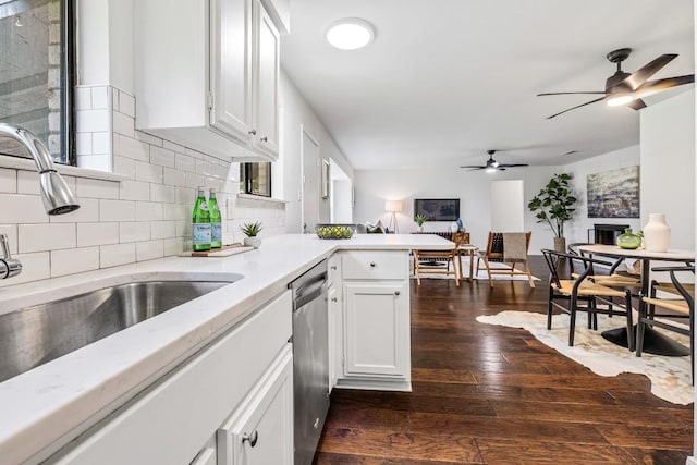 kitchen with white cabinetry, sink, stainless steel dishwasher, kitchen peninsula, and dark wood-type flooring