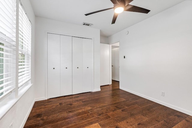 unfurnished bedroom with dark hardwood / wood-style flooring, a closet, and ceiling fan