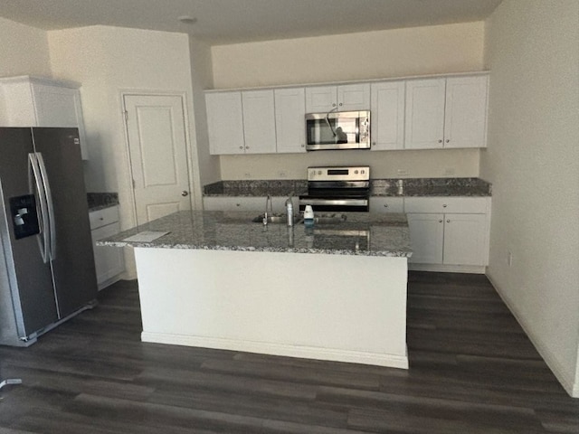 kitchen featuring sink, white cabinets, dark stone counters, a kitchen island with sink, and stainless steel appliances