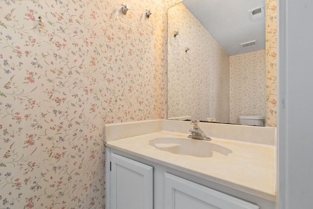 bathroom featuring lofted ceiling, vanity, and toilet